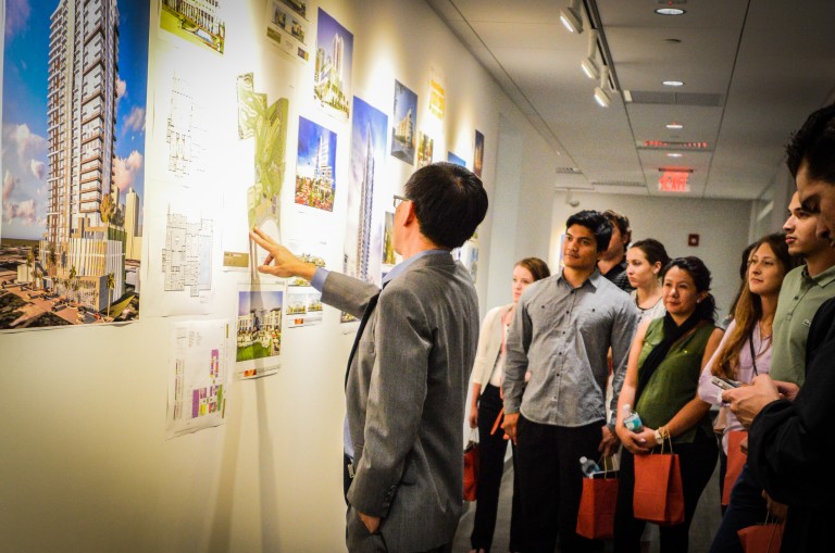 A group discussing architectural drawings and models displayed in the studio